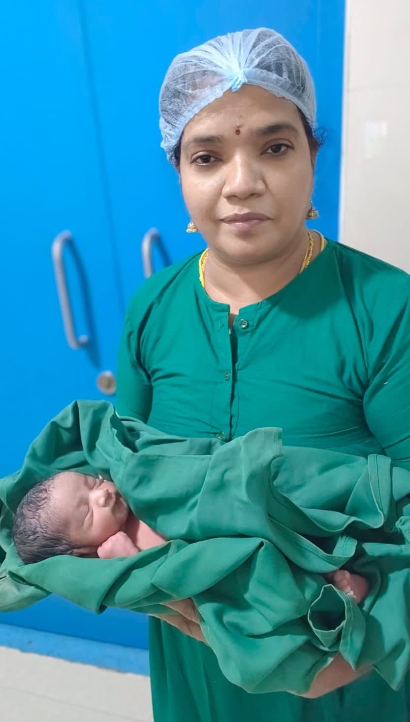 Dr. Sangeetha Balamurugan holding a newborn wrapped in a green sheet